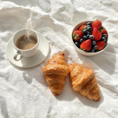Top-down flat lay of a breakfast table with coffee, croissants and fresh berries on white linen, soft daylight, generated at 1:1