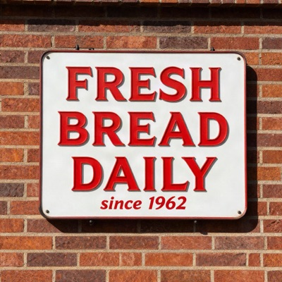 A vintage enamel sign on a brick wall that reads "FRESH BREAD DAILY" in bold red serif letters, with "since 1962" in smaller script below, morning sunlight, generated by Z-Image Turbo
